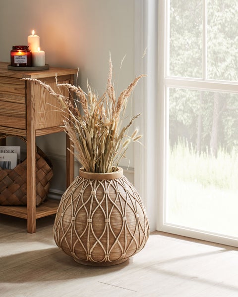 Dekoratives Wohnzimmerambiente mit Holztisch, Kerzen und einer Vase mit Trockenblumen