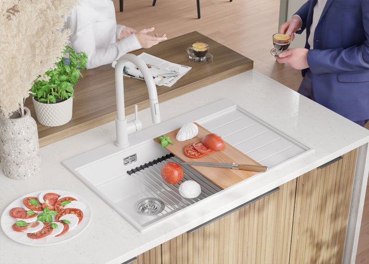 Helle Küche mit Spüle, Armatur, Schneidebrett mit Tomaten und Mozzarella, sowie Personen im Gespräch.