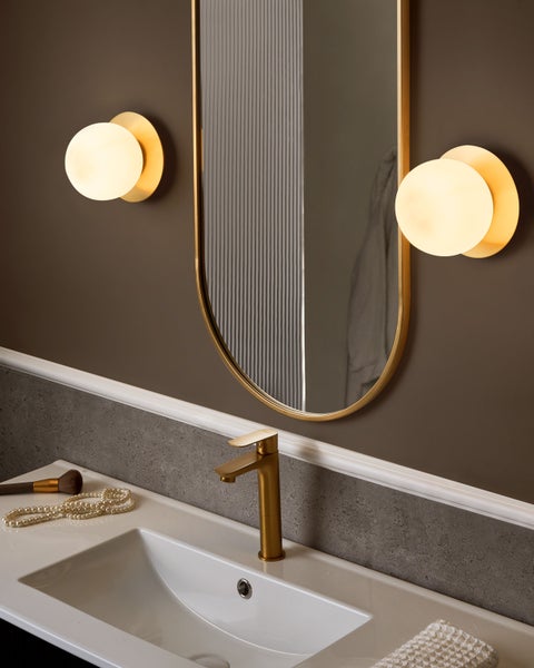 Badezimmer mit Spiegel, Armatur und Beleuchtung