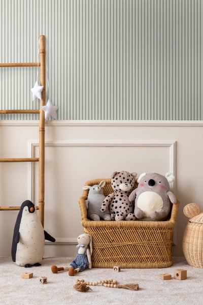 Kinderzimmer mit gestreifter Tapete, Holzleiter und Stofftieren in einem Weidenkorb
