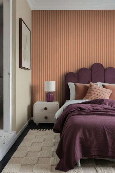 Schlafzimmer mit Bett, Nachttisch und gestreifter Tapete