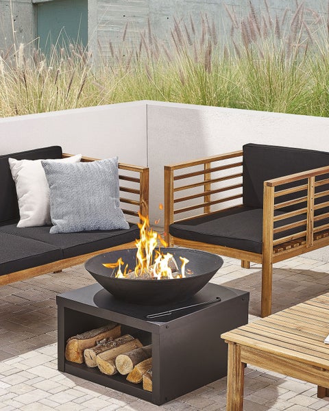 Feuerschale aus Metall mit quadratischem Sockel und integriertem Fach zur Holzaufbewahrung.