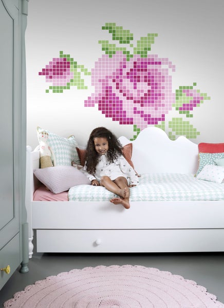 Kinderzimmer mit Mädchen auf einem Bett und Wandtattoo mit Rosenmotiv