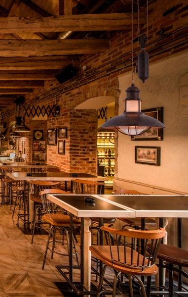 Innenaufnahme eines Restaurants mit Holztischen, Stühlen und einer Hängelampe im Vintage-Stil
