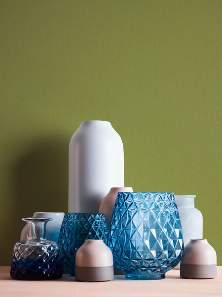 Holztisch mit Dekorationselementen und Pflanze vor einer farbigen Wand