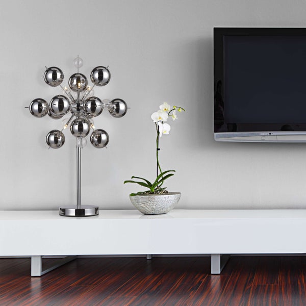 Dekorative Szene mit einer Tischleuchte mit Kugeln, einer Orchidee und einem Fernsehgerät auf einem Lowboard