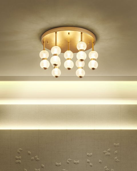 Moderne Deckenleuchte mit runder goldfarbener Basis und mehreren strukturierten Glaskugeln in einem hellen Innenraum.