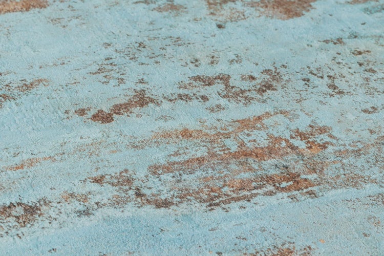 Dekorative Wand mit blau-brauner Textur neben einem Hocker mit Kosmetikprodukten