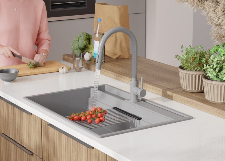 Küchenszene mit Spüle, Armatur und Person beim Gemüseschneiden