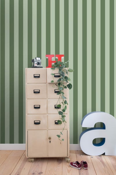 Dekoratives Zimmer mit gestreifter Tapete, Aktenschrank, Pflanze und Accessoires