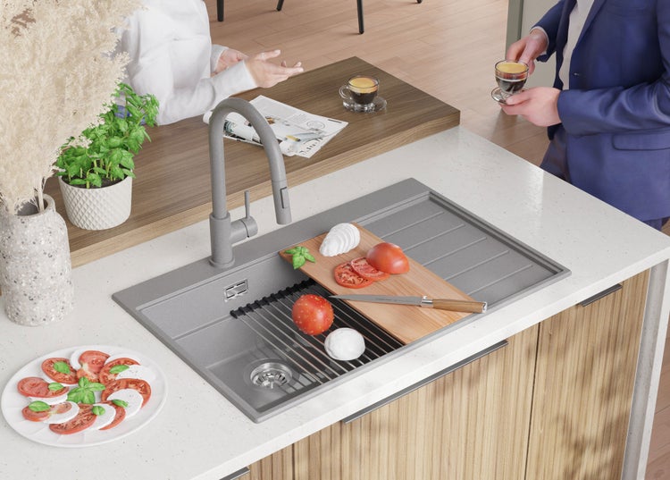 Küchenszene mit Spüle, Armatur, Schneidebrett, Mozzarella, Tomaten und Personen