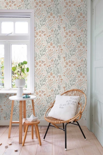 Tapete mit botanischem Blumenmuster und Blättern in einem hellen Zimmer mit Rattansessel und Beistelltisch aus Holz.