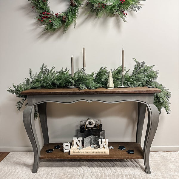 Dekoratives Arrangement mit Tisch, Girlande, Kerzen und weihnachtlichen Akzenten für festliche Atmosphäre