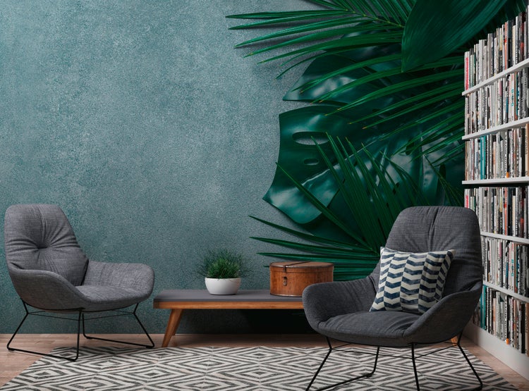 Modernes Wohnzimmer mit zwei grauen Polstersesseln, einem niedrigen Holztisch, geometrischem Teppich und strukturierter Wand mit Palmenmotiven.