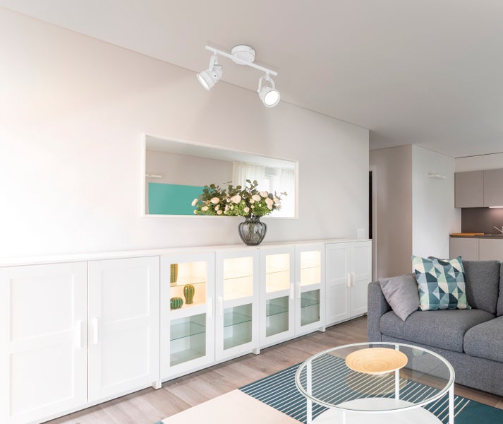 Wohnzimmer mit weißer Anbauwand, Couchtisch und Deckenspots