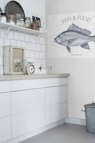 Helle Küche mit Fliesenwand, Regal, Küchenutensilien und Wanddekoration mit Fischmotiv.