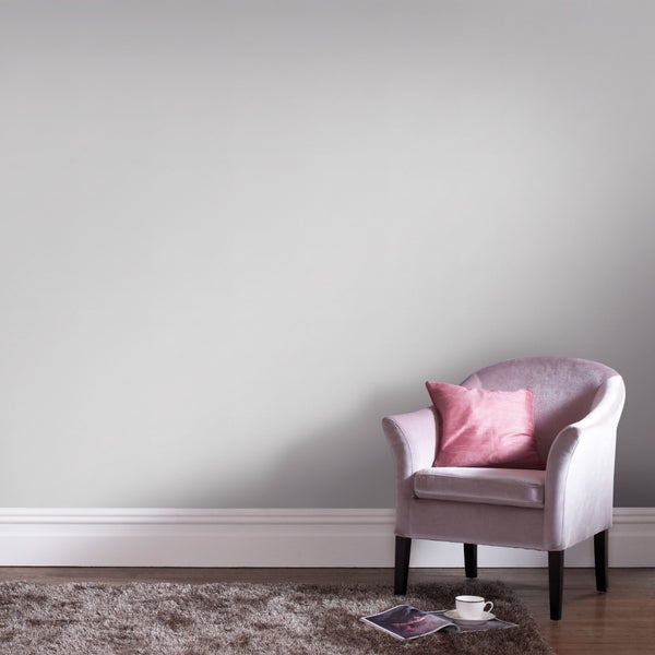 Modernes Wohnzimmer mit hellgrauer Wandfarbe, einem rosa Samtsessel mit Kissen und einem braunen Hochflor-Teppich auf Holzboden.
