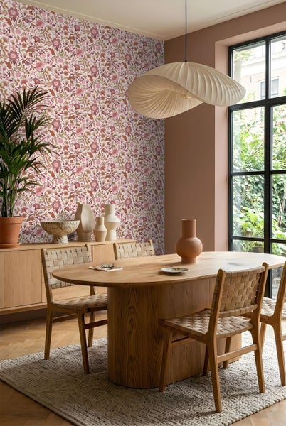 Vliesbehang mit floralem Muster in einem hellen Esszimmer mit ovalem Holztisch, geflochtenen Stühlen und Parkettboden.