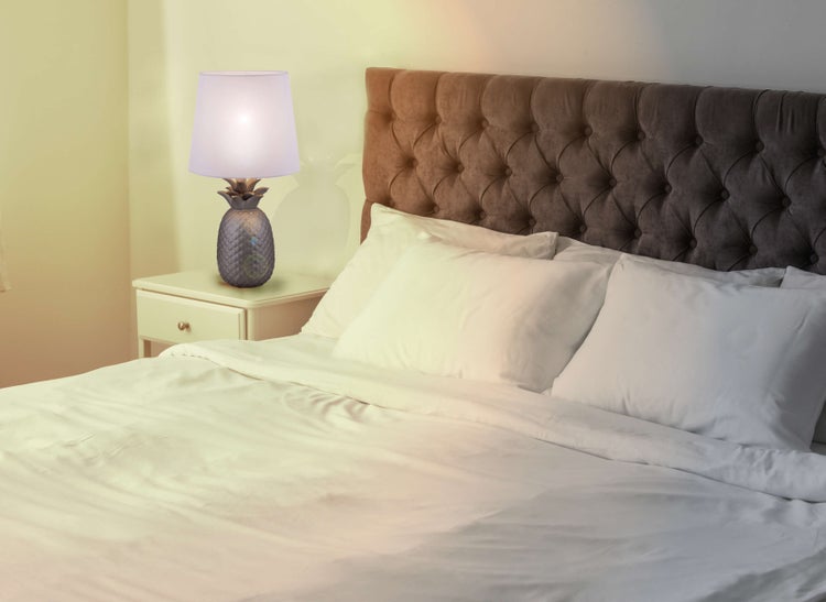 Schlafzimmer mit Bett, Nachttisch und Ananaslampe