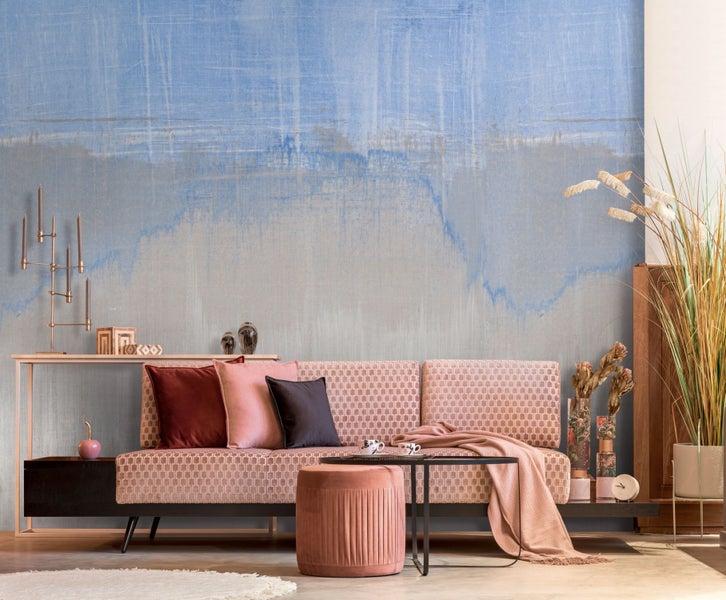 Wohnzimmer mit Sofa, Hocker und Dekorationen vor einer blauen Wand