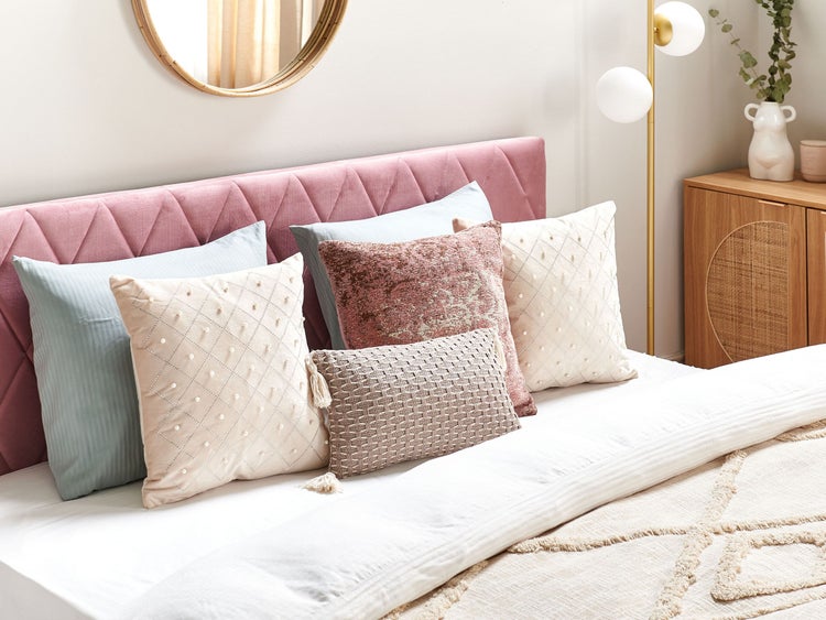 Dekoratives Schlafzimmer mit Kissen auf dem Bett und Spiegel an der Wand