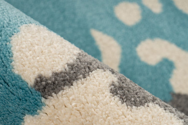 Nahaufnahme eines blau-grau-weiß gemusterten Hochflor-Teppichs mit weicher Textur.