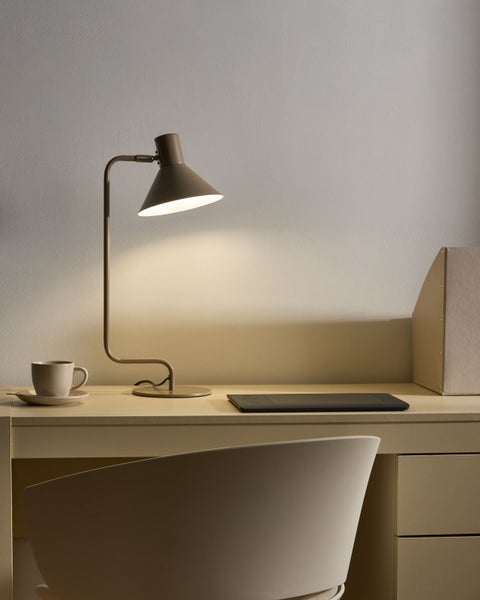 Schreibtischlampe mit konischem Schirm in einem organisierten Homeoffice mit Grafiktablett und Stuhl in hellem, einfarbigem Design.