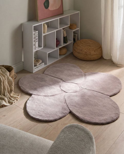 Hochflor-Teppich in Blumenform auf hellem Holzboden in einem hellen Zimmer mit weißem Regal und Korb-Accessoires.