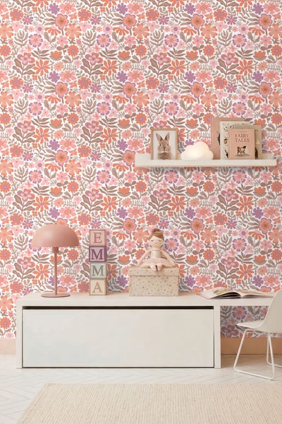 Hell gestaltetes Kinderzimmer mit floral gemusterter Tapete, weißem Sideboard, einer Schreibtischlampe und einem Wandregal mit Dekoration.