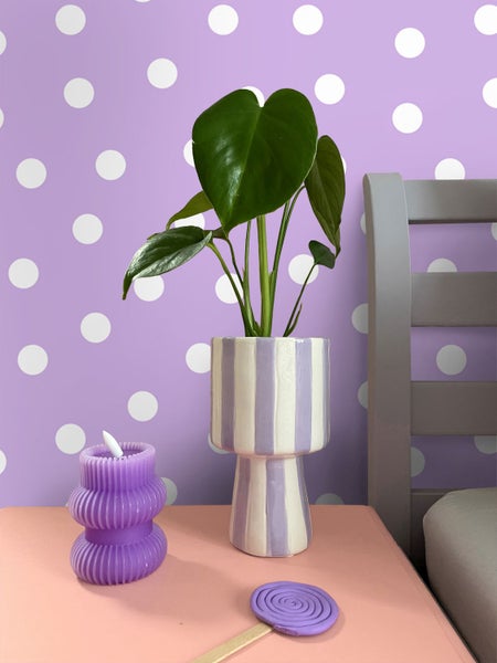 Dekorative Szene mit Pflanze in gestreiftem Topf, Kerze und Deko-Lutscher