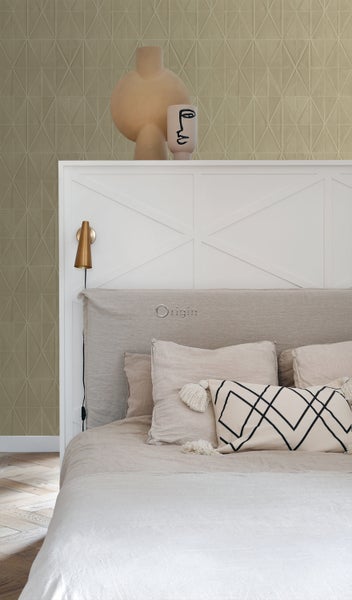 Ein helles Schlafzimmer mit einem Bett, Kissen und Dekorationsartikeln auf dem Betthaupt.