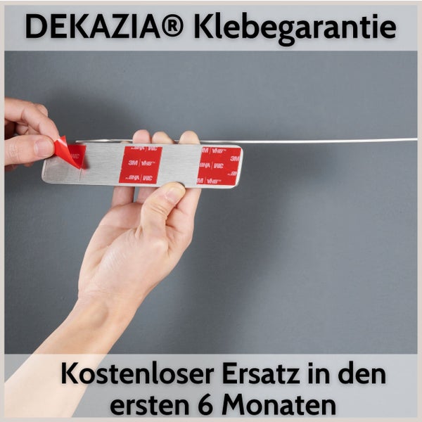 Hände ziehen die Schutzfolie von den 3M VHB Klebestreifen einer Metallhalterung ab, Dekazia Klebegarantie für sechs Monate.