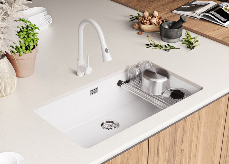 Küchenspüle aus hellem Stein mit Abtropfgestell, Armatur und Geschirr