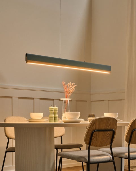 Moderne LED-Pendelleuchte im Balkendesign aus Metall und Holz über einem gedeckten Esstisch in einem hellen Esszimmer.