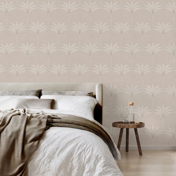 Vliestapete mit Palmenmuster im Schlafzimmer hinter einem Bett mit Kissen und Decke.