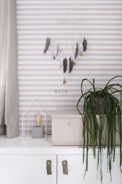 Dekoratives Kinderzimmer mit Feder-Mobile, Tischleuchte und Zimmerpflanze auf einer Kommode