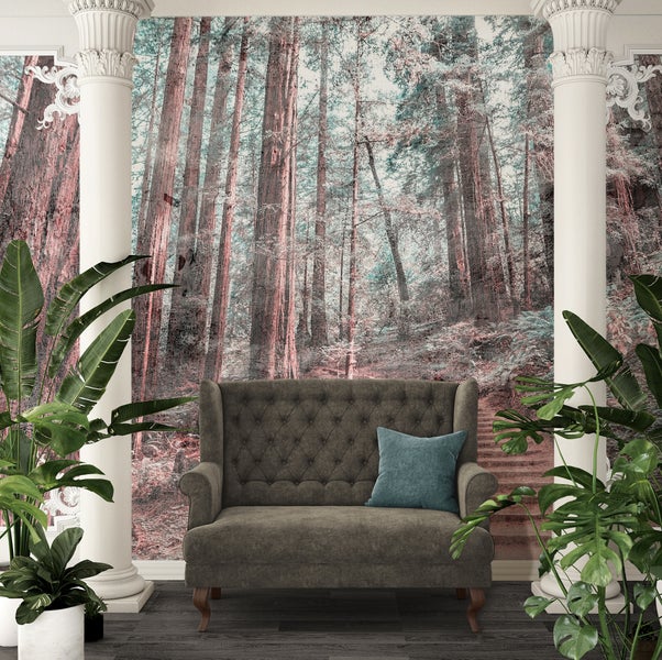 Vliestapete mit Redwood-Waldmotiv zwischen zwei Säulen. Davor ein graues Sofa und Zimmerpflanzen in einem hellen, klassischen Wohnzimmer.