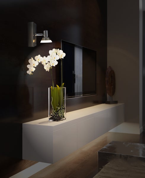 Wohnzimmer mit Wandleuchte, Fernseher und Orchidee in einer Vase auf einem Sideboard.