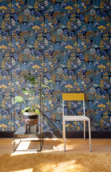 Raumansicht mit gemusterter Tapete, Pflanze und Stuhl