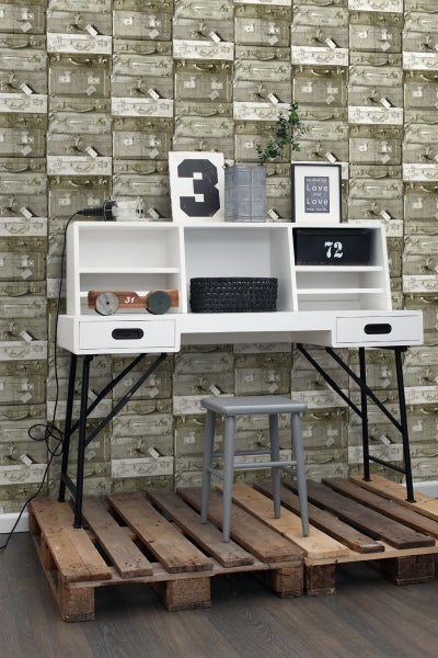 Szene mit Schreibtisch auf Holzpalette vor einer Wand mit Koffertapete