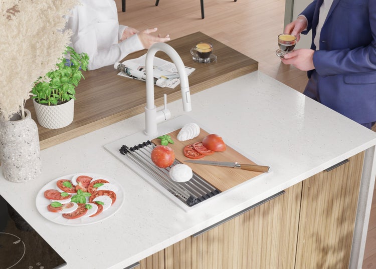 Küchenszene mit Spüle, Armatur, Schneidebrett, Tomaten, Mozzarella und Basilikum