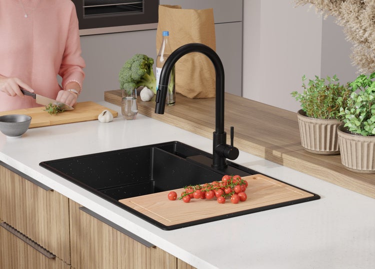 Küchenszene mit Spüle, Armatur und Person beim Gemüseschneiden