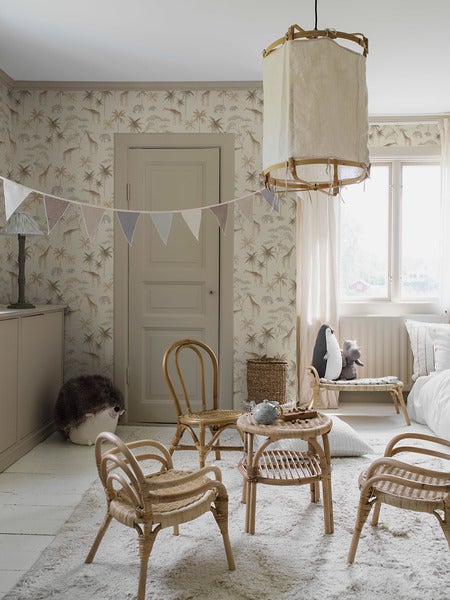 Kinderzimmer mit Tapete, die Giraffen, Elefanten und Palmen zeigt, dazu eine Tür und ein Regal mit Spielzeug