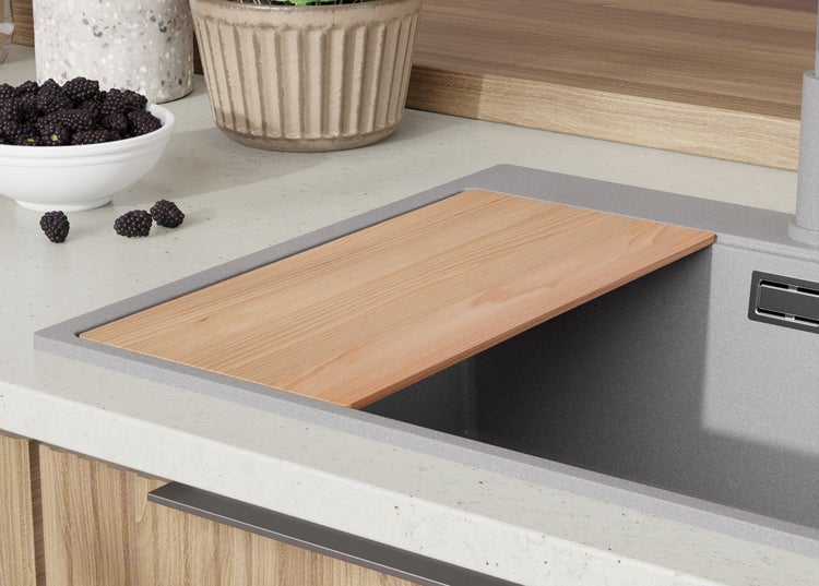 Küchenspüle mit Holzschneidebrett, dazu eine Schale Brombeeren und eine Topfpflanze