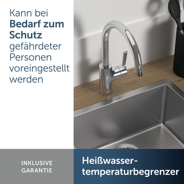 Küchenarmatur mit Heißwassertemperaturbegrenzer an einer Edelstahlspüle auf einer Holzarbeitsplatte mit Textoverlay zur Garantieleistung.