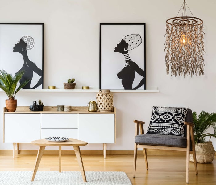 Wohnzimmer mit Kommode, Dekoration, Sessel, Tisch, Zimmerpflanzen, Wandbildern und Hängelampe