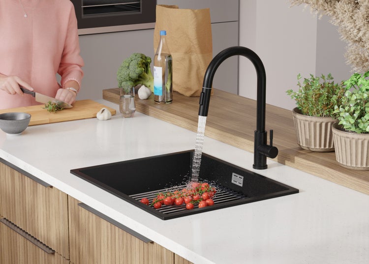 Küchenspüle mit Armatur, Gemüse und Person beim Kochen.