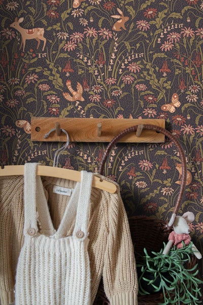 Kinderzimmer mit dunkler Mustertapete, Holz-Kinderbett mit Baldachin, gemusterter Decke und Vorhängen.