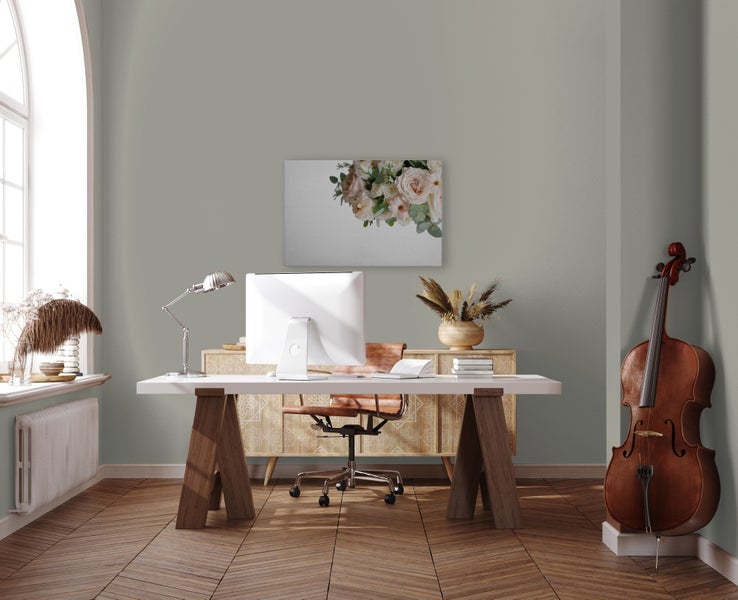 Helles, modernes Arbeitszimmer mit Holzschreibtisch, Bürostuhl und einem Cello vor einer Wand gestrichen in einem gedeckten Farbton.