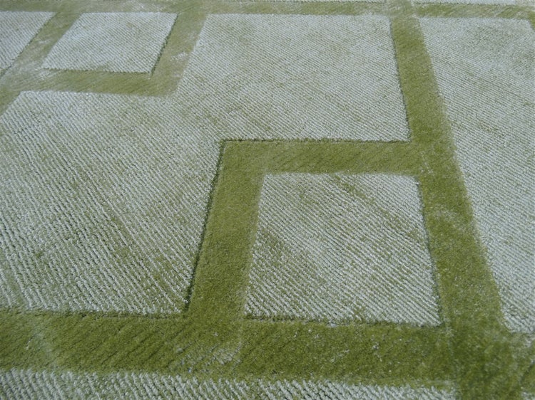 Grüner Teppich mit geometrischem Quadratmuster und Hoch-Tief-Struktur.